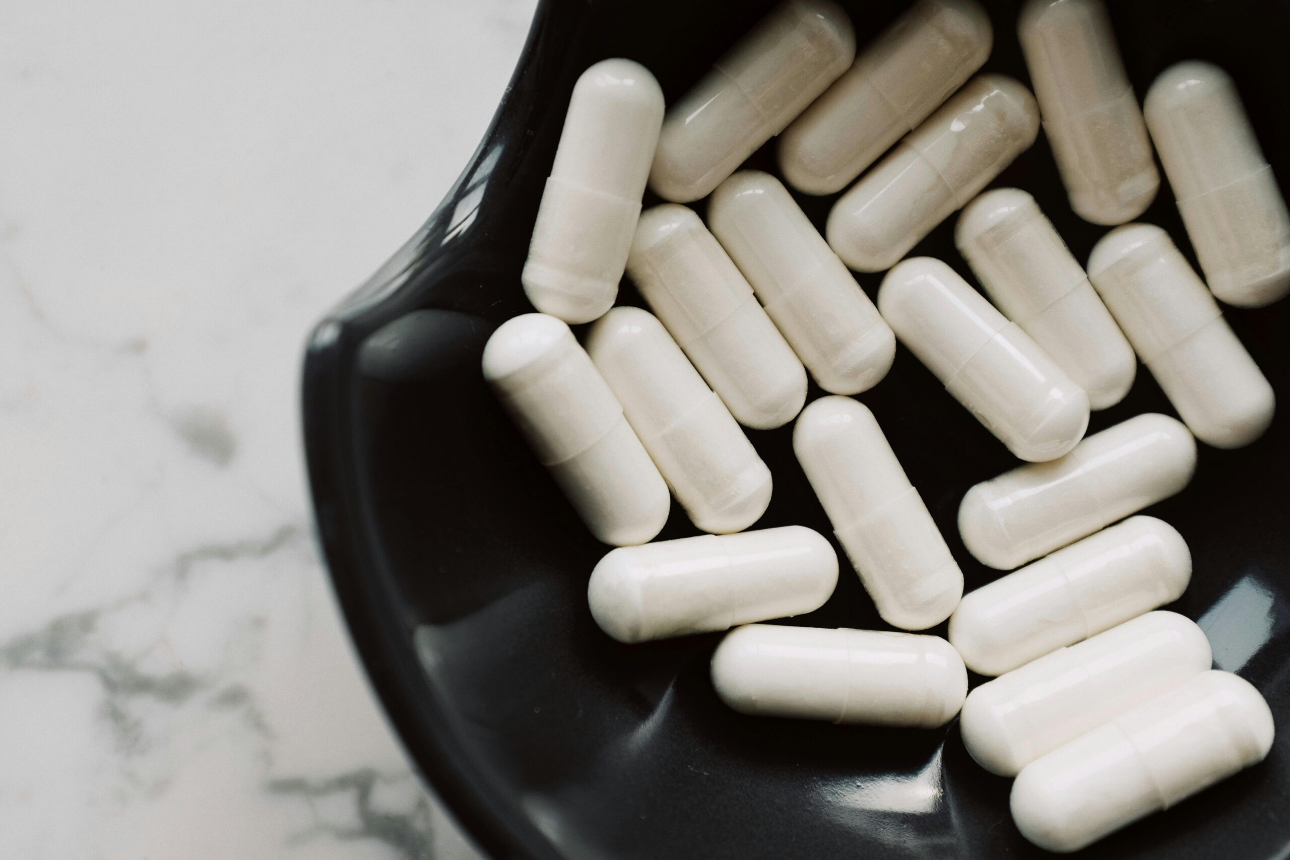 A detailed shot of white capsules in a black bowl, highlighting healthcare concerns.