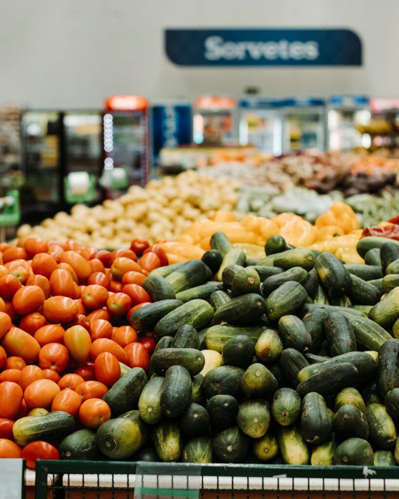 Vibrant cucumbers and tomatoes on display in a Brazilian supermarket produce section.