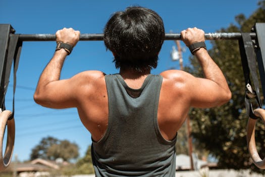 Man doing pull-ups on a bar outdoors, emphasizing fitness and strength.
