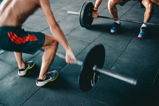 Two men lifting barbells showing strength and effort in a gym setting.